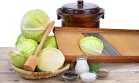 White cabbage and all of the ingredients and tools for making  sauerkraut.