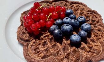 Bild der fertiggestellten "Bananen-Schoko-Waffeln mit Lycopin" mit Beeren dekoriert.
