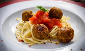 Fertig zubereitete "Knusprig-würzige Linsenbällchen" zusammen mit Pasta auf einem Teller. Fertig zubereitete "Knusprig-würzige Linsenbällchen" zusammen mit Pasta auf einem Teller.