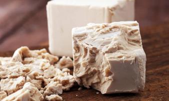 Запеченные дрожжи рассыпались и дрожжевой блок для выпечки на заднем плане.